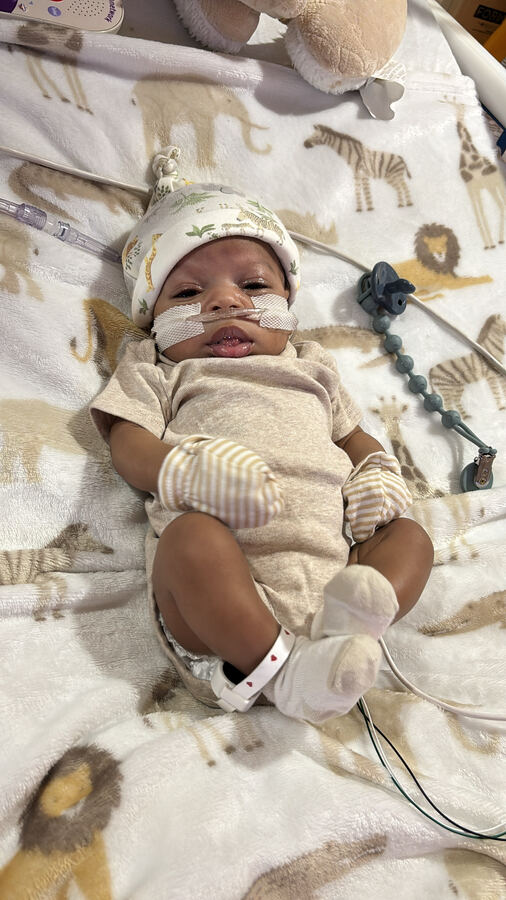 Myles resting in a safari-print onesie.