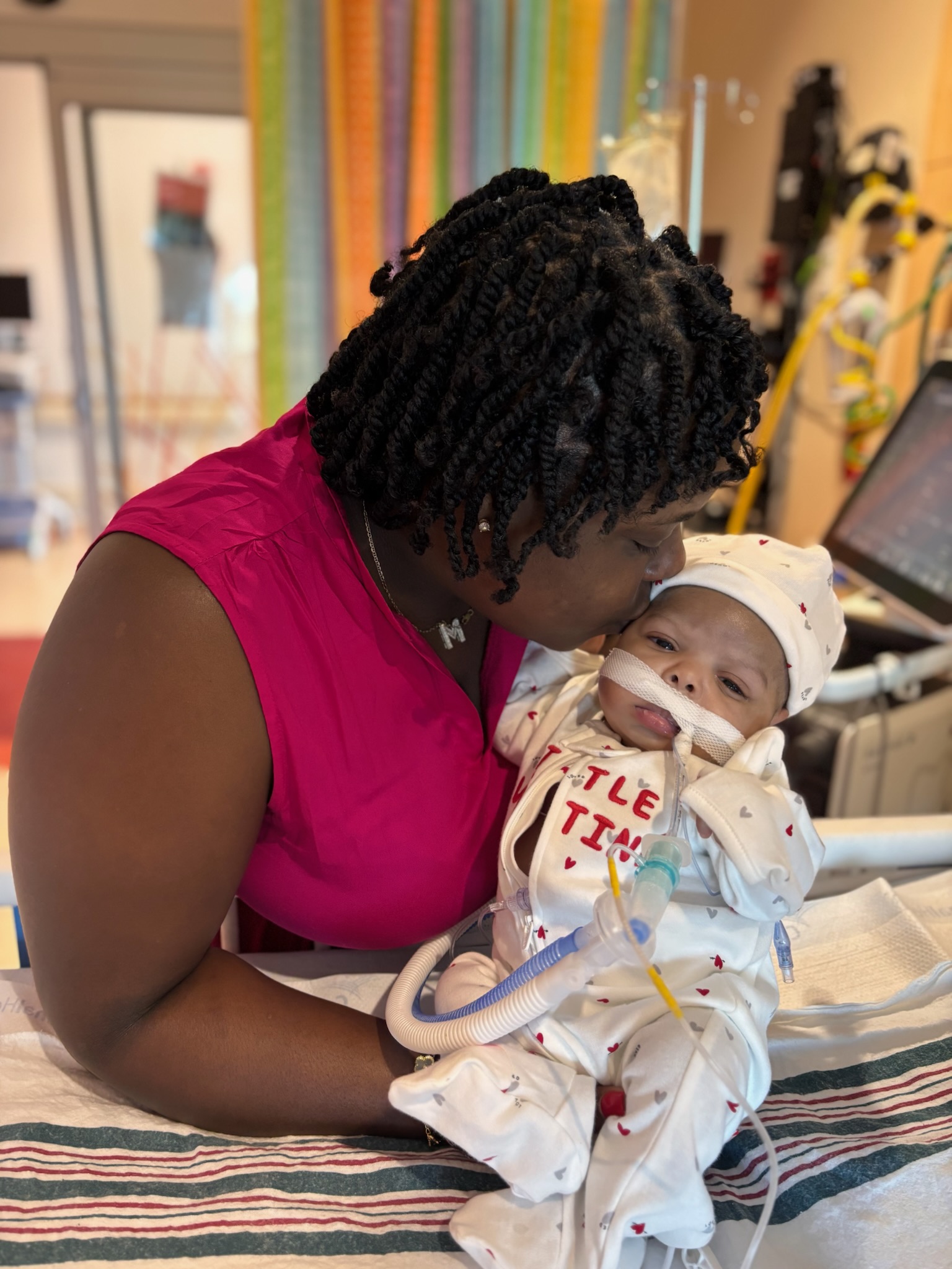 A mother kissing her baby, Myles, while he is cared for in the hospital.